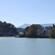 A house near a gazebo, trees, mountains and a lake